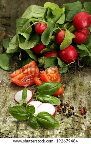 bunch of radishes with slices of tomato and basil