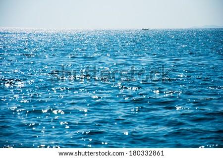 Long-tail boat on sparkling blue sea water surface