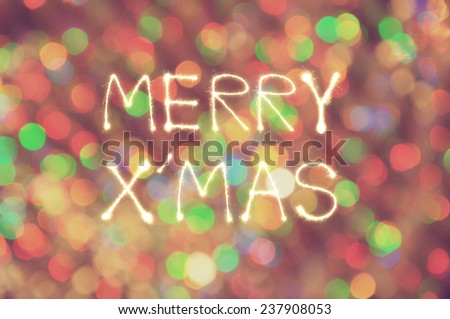 Merry X\' Mas writing sparkler firework with defocused colorful light blur background