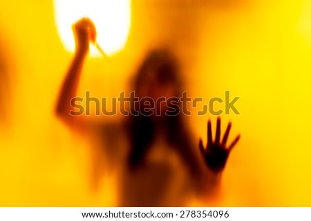 Shadow woman figure with a  scissors behind blurred glass