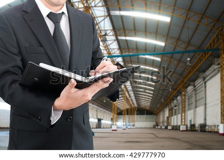 Professional businessman evaluation factory with blurred construction factory building site background, industrial business concept