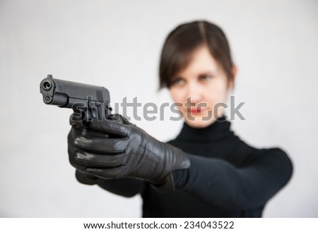 Young woman holding a pistol, neutral background