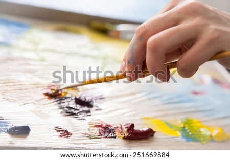 Painter\'s hand holding a brush and blending oil colours