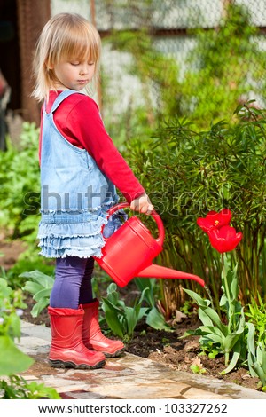 Little girl watering red tulip with red watering can