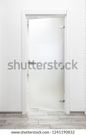 Minimalist modern office interior with white wall and frosted glass door ajar