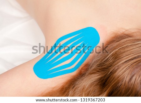 Shoulder with blue elastic therapeutic tape applied for treating pain and disability from athletic injury or other physical disorder - Kinesiotaping concept