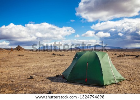 Camping tent on a rocky Dreki camping site near Askja caldera and Ódáðahraun lava field in Highlands of Iceland, Scandinavia. Herdubreid tuya volcano mountain and rainy clouds is seen in background