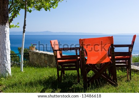 Red chairs in open-air greek cafe overlooking the sea gulf