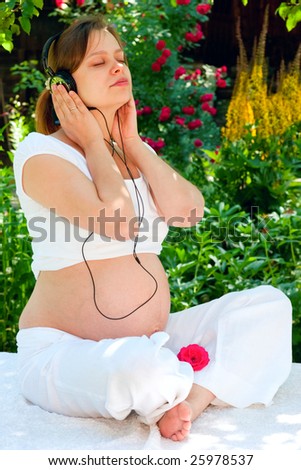 Young woman listening to a music at summer garden