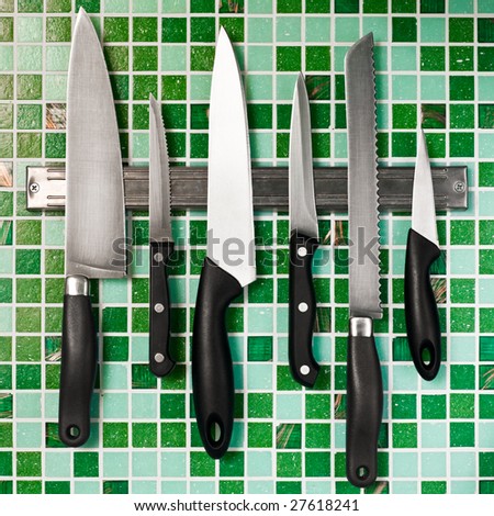 Kitchen knives on green mosaic wall