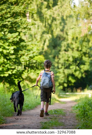 Young boy walking with black dog - stock photo