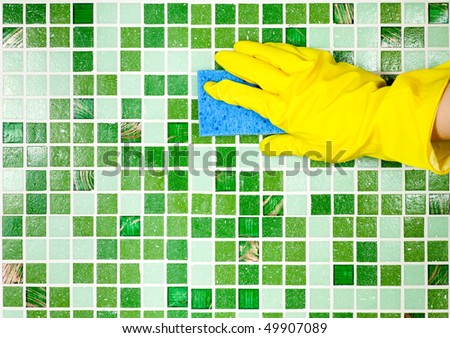 Hand in yellow protective glove  cleaning mosaic wall