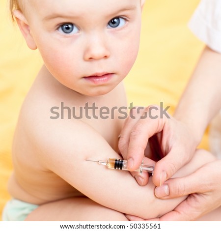 Doctor giving a child an intramuscular injection in arm, focus on syringe