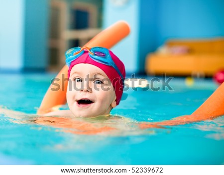 stock photo Happy little girl learning to swim with pool noodle