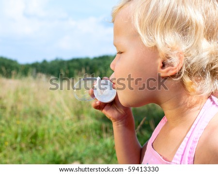 Cute little girl making  soap bubbles outdoors