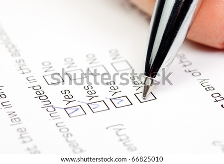 Hand with pen over blank check box Yes in application form