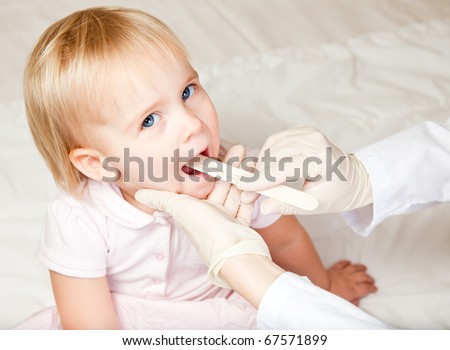 Pediatrician examining little girl\'s throat with tongue depressor