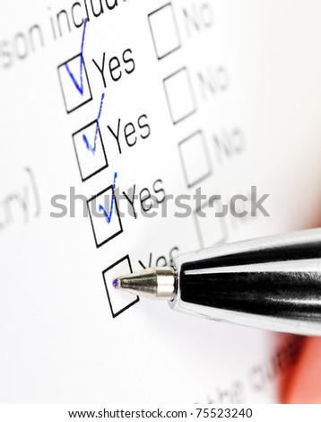 Hand with pen over blank check box Yes in application form
