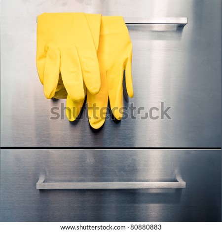 Yellow protective gloves hanging on kitchen cab handle