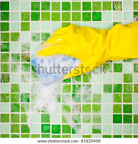 Hand in yellow protective glove  cleaning mosaic wall