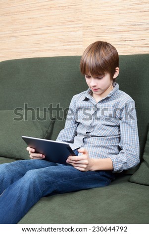 Portrait of 12 years boy wearing casual clothing using new touch pad at home