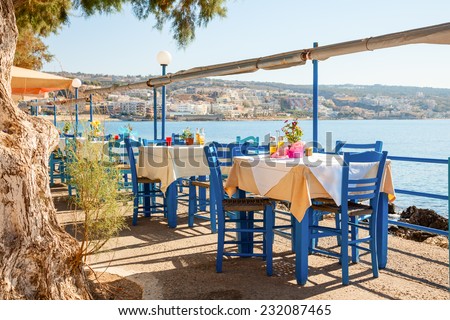 Empty greek cafe terrace in Heraklion, Crete overlooking the sea with typical wooden chairs