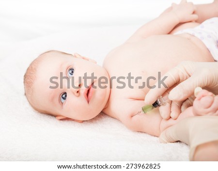 Pediatrician giving a three month baby girl  intramuscular injection in arm. Child looking anxiously at a doctor