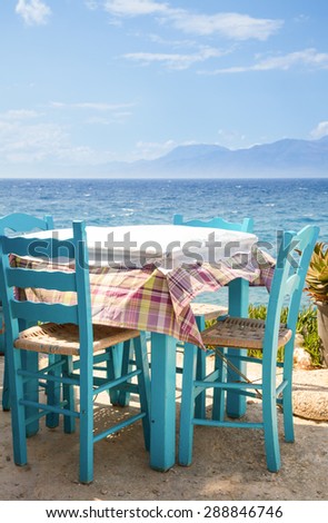 Blue wooden table with chairs of outdoor greek cafe overlooking the sea