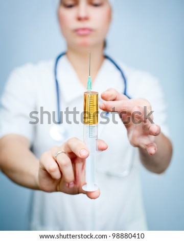 Doctor holding big syringe with yellow liquid ready for injection