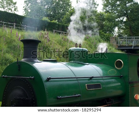 A green steam train  at a station