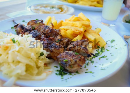 Grilled shashlik with french fries on plate.\
Mediterranean meal.