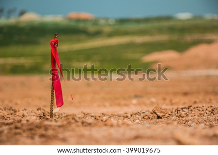 Metal survey peg with red flag on construction site.