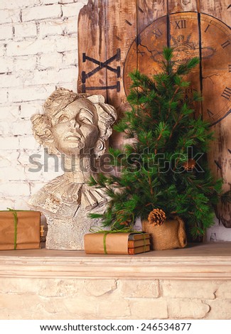 Plaster bust, fur tree with cones, vintage wood clock decor standing on the fireplace mantel