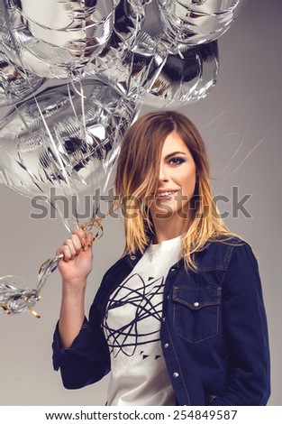 Beautiful romantic teenager girl posing in blue jeans shirt with ombre hair and silver balloons in her hands