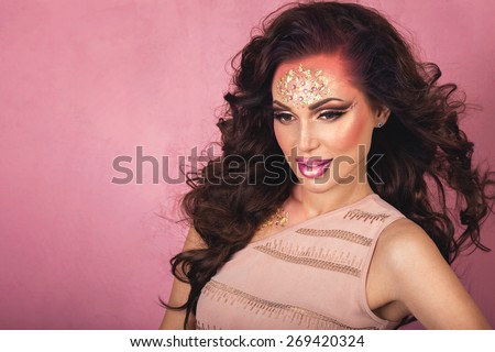 Fashion Art Beauty Portrait. Beautiful brunette woman with fantasy creative make up and blowing hair. Pink background copy space.