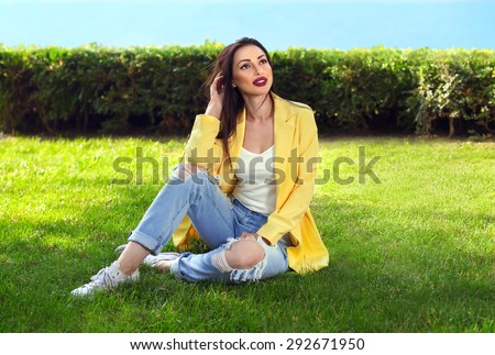 Beautiful dreaming woman sitting on the grass