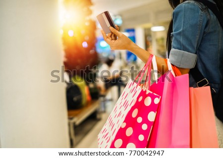 Asia beautiful woman carrying shopping bag and walking in the department store.young lady shopping by using credit card on weekend.