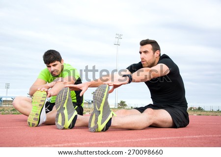 two men stretching in running track