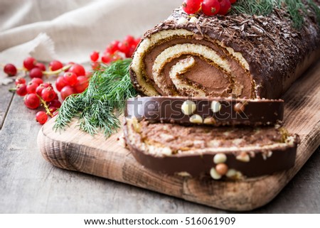 Chocolate yule log christmas cake with red currant on wooden background.closeup