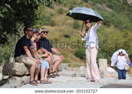 EPHESUS, TURKEY - June, 06, 2014: A group of tourists gather around a tour guide in the celsus library area of Ephesus in order to hear the guide tell them about the site.