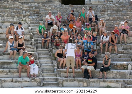 Ephesus, Turkey - June 25, 2014: A group of tourists gather around a tour guide in the celsus library area of Ephesus in order to hear the guide tell them about the site.