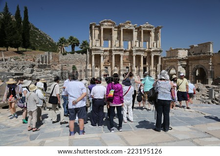 Ephesus, Turkey - June, 26, 2014: A group of tourists gather around a tour guide in the celsus library area of Ephesus in order to hear the guide tell them about the site.