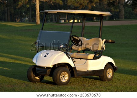 A golf cart sits on the fairway of a golf course at a private country club.