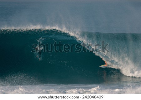 A surfer rides through a tube on an ocean wave.