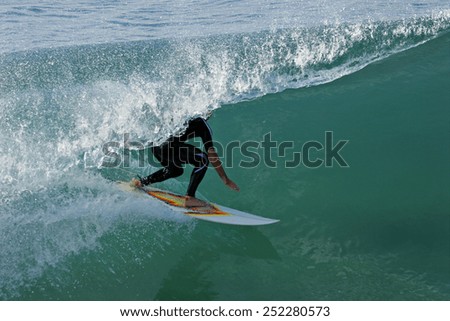 A surfer in a wetsuit rides a tube on a beautiful ocean wave.