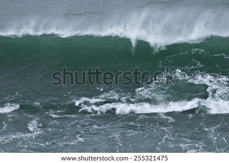 A huge blue wave crashes into the rocks as it ends its journey across the ocean.