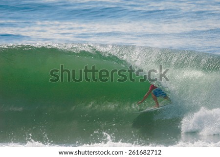 A surfer rides a tube on a beautiful green wave.