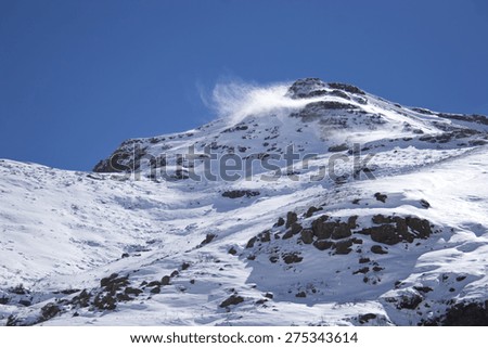 Wind whips snow off the summit of a mountain of a snow covered mountain in the Maluti range in rural Lesotho, Africa.
