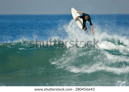 A surfer executes a radical aerial on a blue ocean wave.