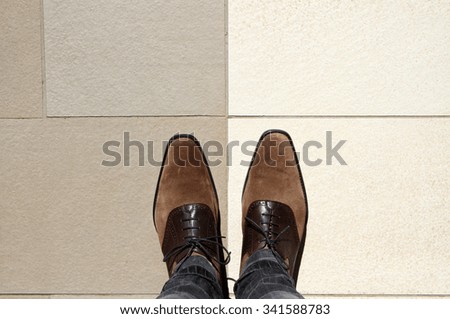 Perspective of a pair of smart shoes being worn by a man looking down.